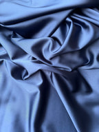Dettaglio tessuto doppio raso fluido blu medio, superficie liscia e lucente per abbigliamento