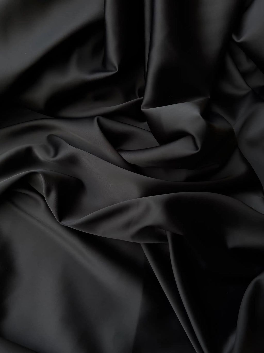 Dettaglio tessuto doppio raso fluido nero intenso, superficie liscia e lucente per abbigliamento
